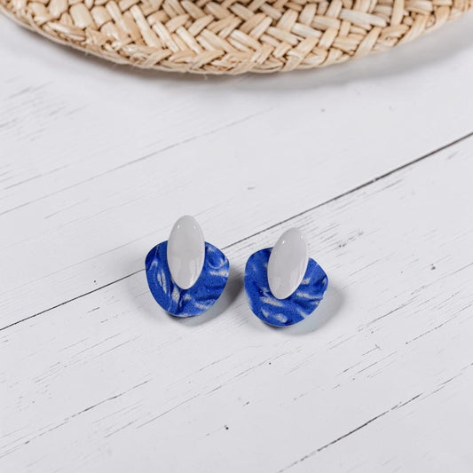 Pendientes artesanales de arcilla polimérica modelo Nirai, color azul intenso con textura marmolada y blanco, cierre de botón
