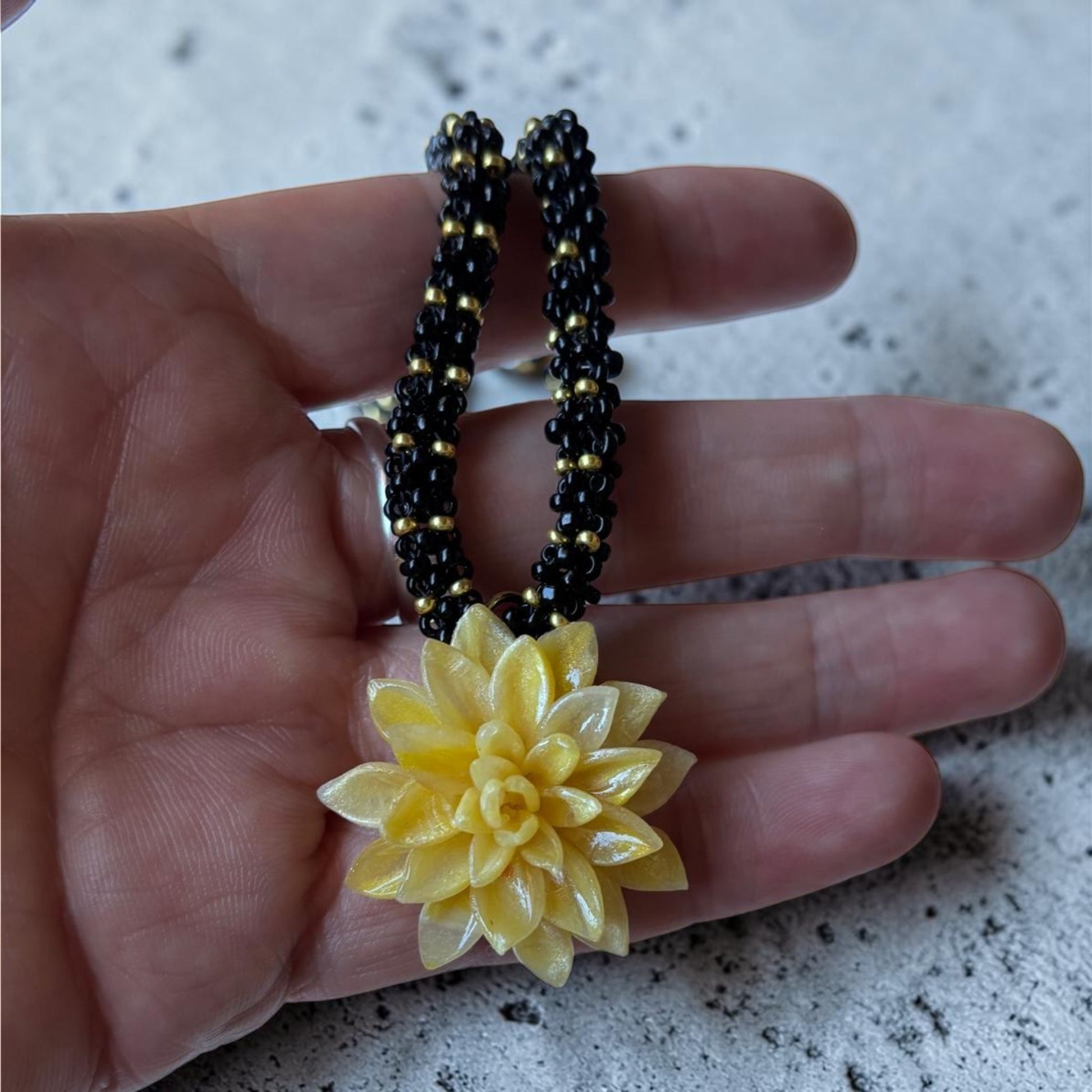 Detalle de cerca del colgante floral amarillo Modelo Galatzó, mostrando la textura de los pétalos de arcilla polimérica y el tejido artesanal del cordón.