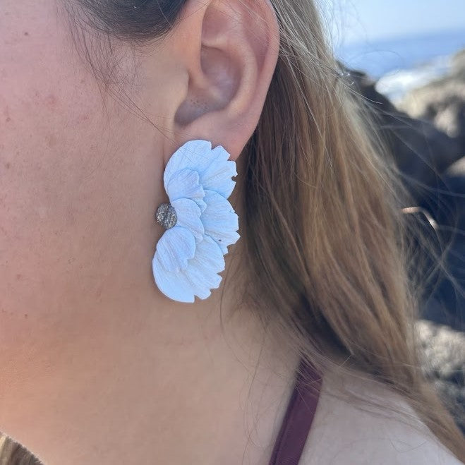Detalle de pendiente artesanal Solleric de media flor azul nube en arcilla polimérica puesto en la oreja