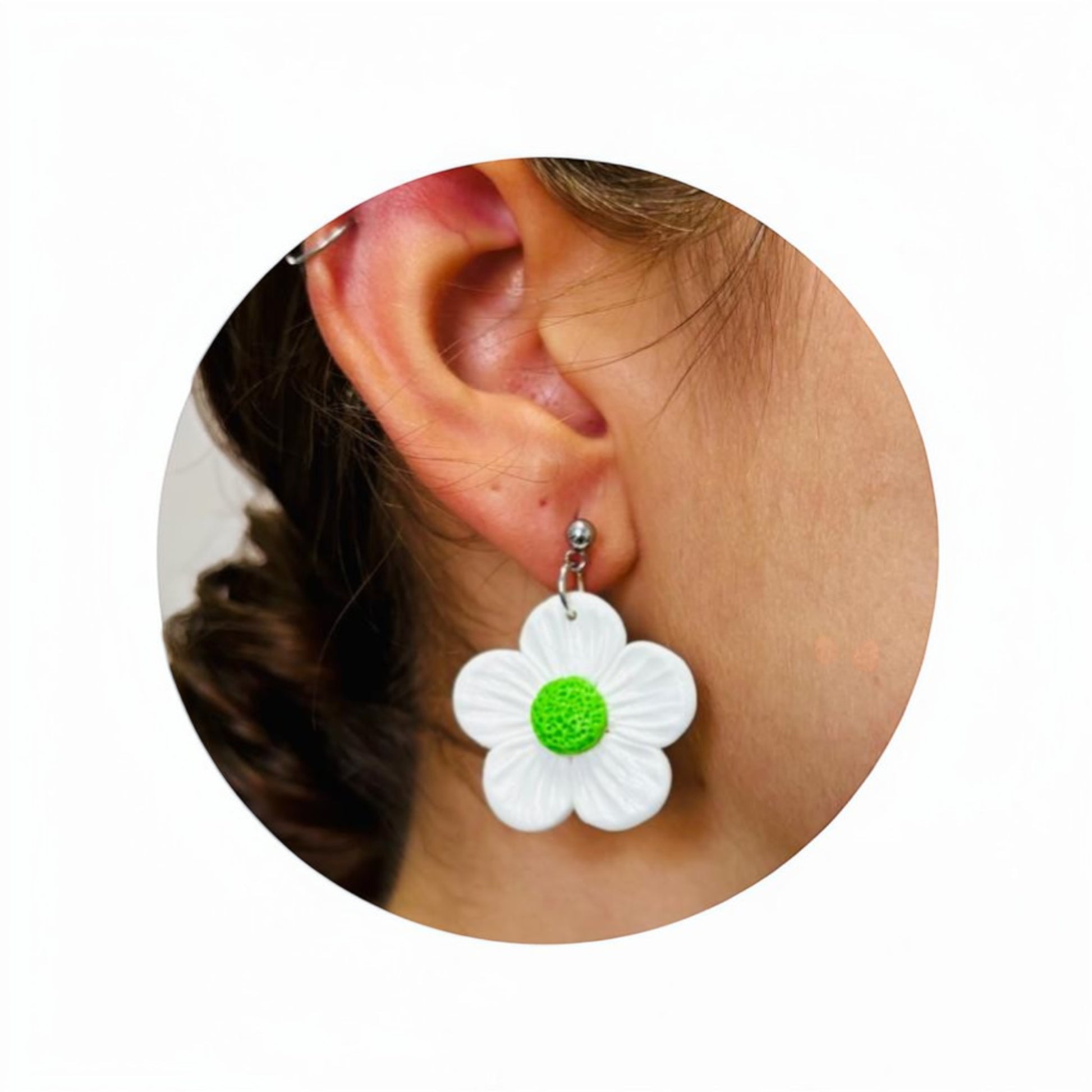 Primer plano de oreja con pendiente artesanal de margarita blanca y centro verde de arcilla polimérica mostrando tamaño y caída real