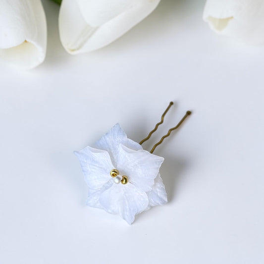 Horquilla para el pelo de novia con flor blanca artesanal y horquilla dorada, fotografiada junto a tulipanes blancos - joyería nupcial Mallorca
