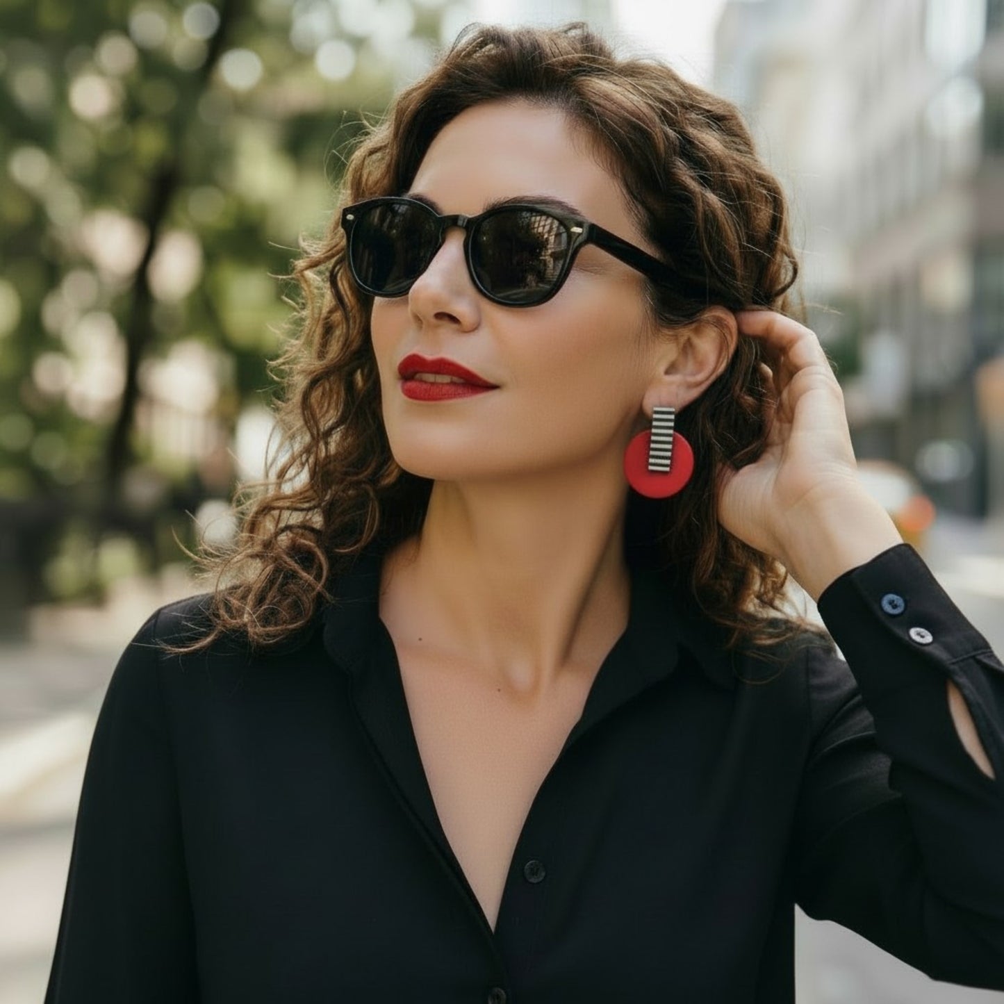 Modelo con gafas de sol y labios rojos luciendo pendientes geométricos de rayas y color rojo