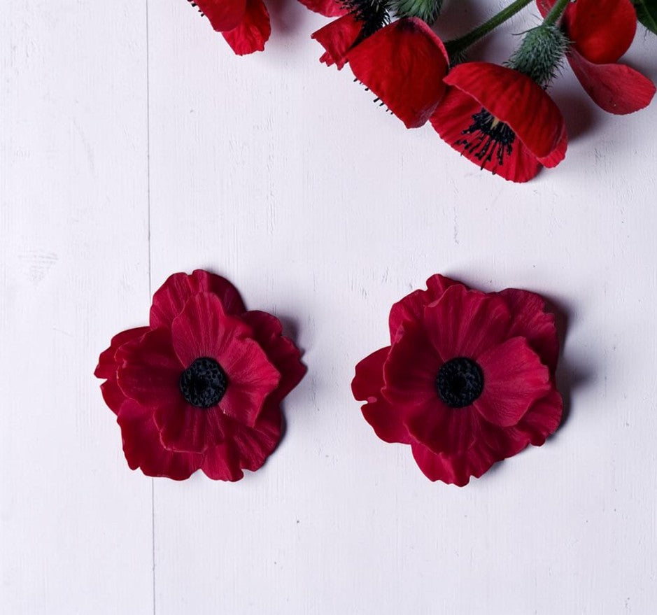 Par de pendientes Poppy Soul en arcilla polimérica color rojo, talla L, sobre fondo de madera blanca con amapolas naturales
