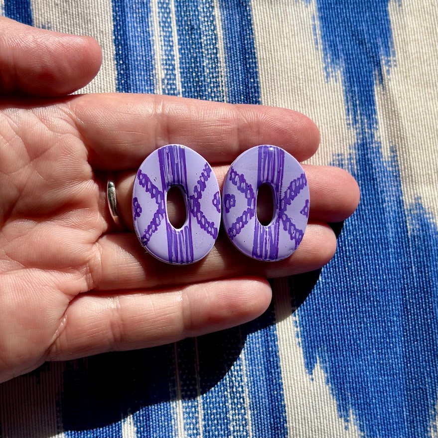 Pendientes llengos mar color lila sostenidos en mano para apreciar su tamaño y detalles del estampado