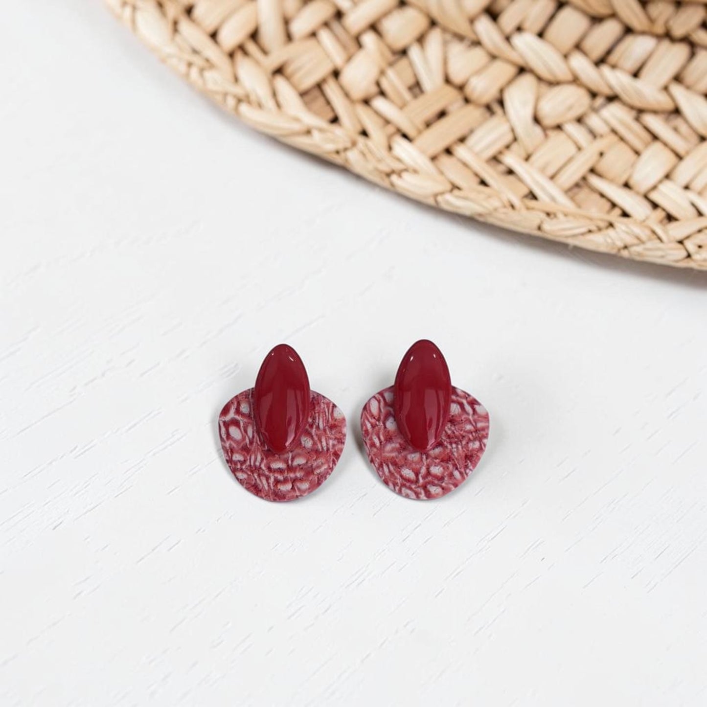 Pendientes artesanales de arcilla polimérica modelo Nirai, color burdeos con textura rugosa, cierre de botón