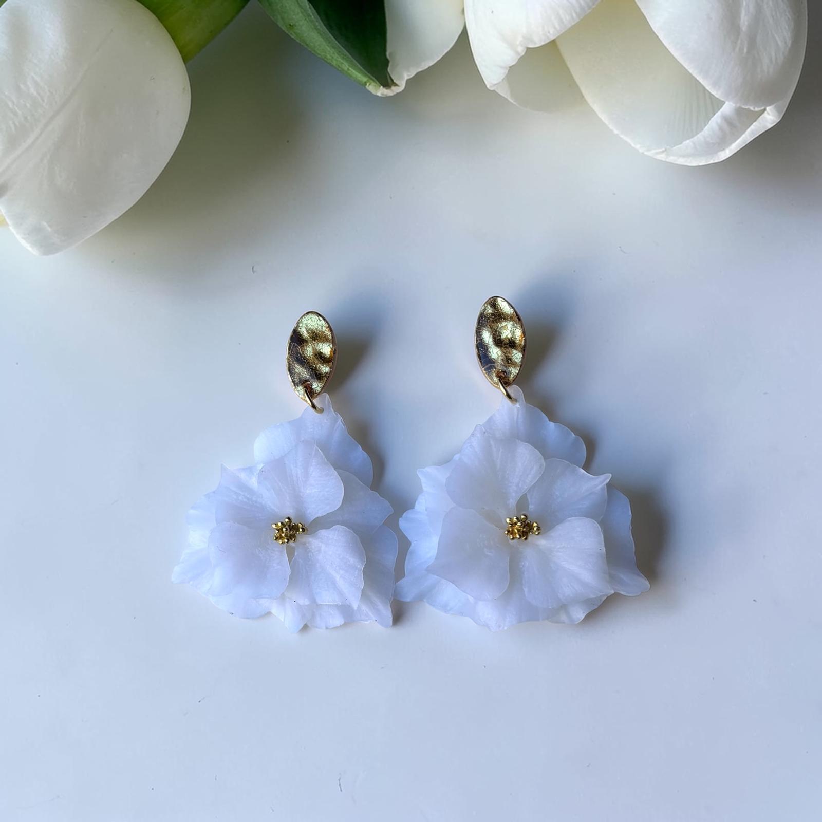 Pendientes florales artesanales blancos con base dorada, fotografiados junto a tulipán blanco - joyería nupcial Mallorca
