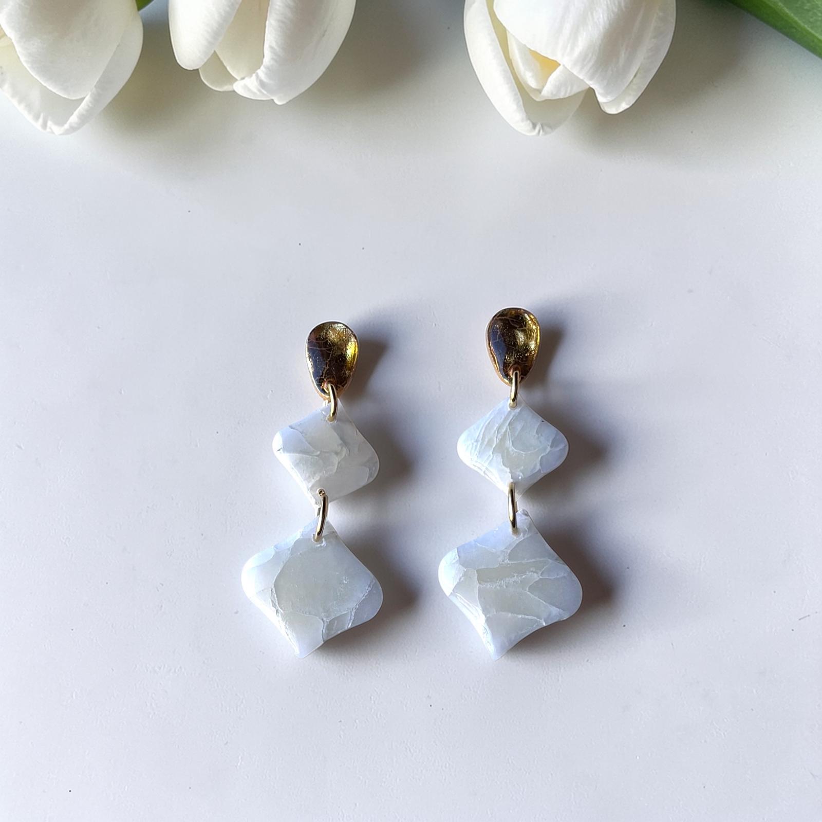 Pendientes geométricos artesanales Son Berga de arcilla polimérica efecto piedra blanca con enganche dorado, fotografiados con tulipanes blancos - joyería nupcial Mallorca
