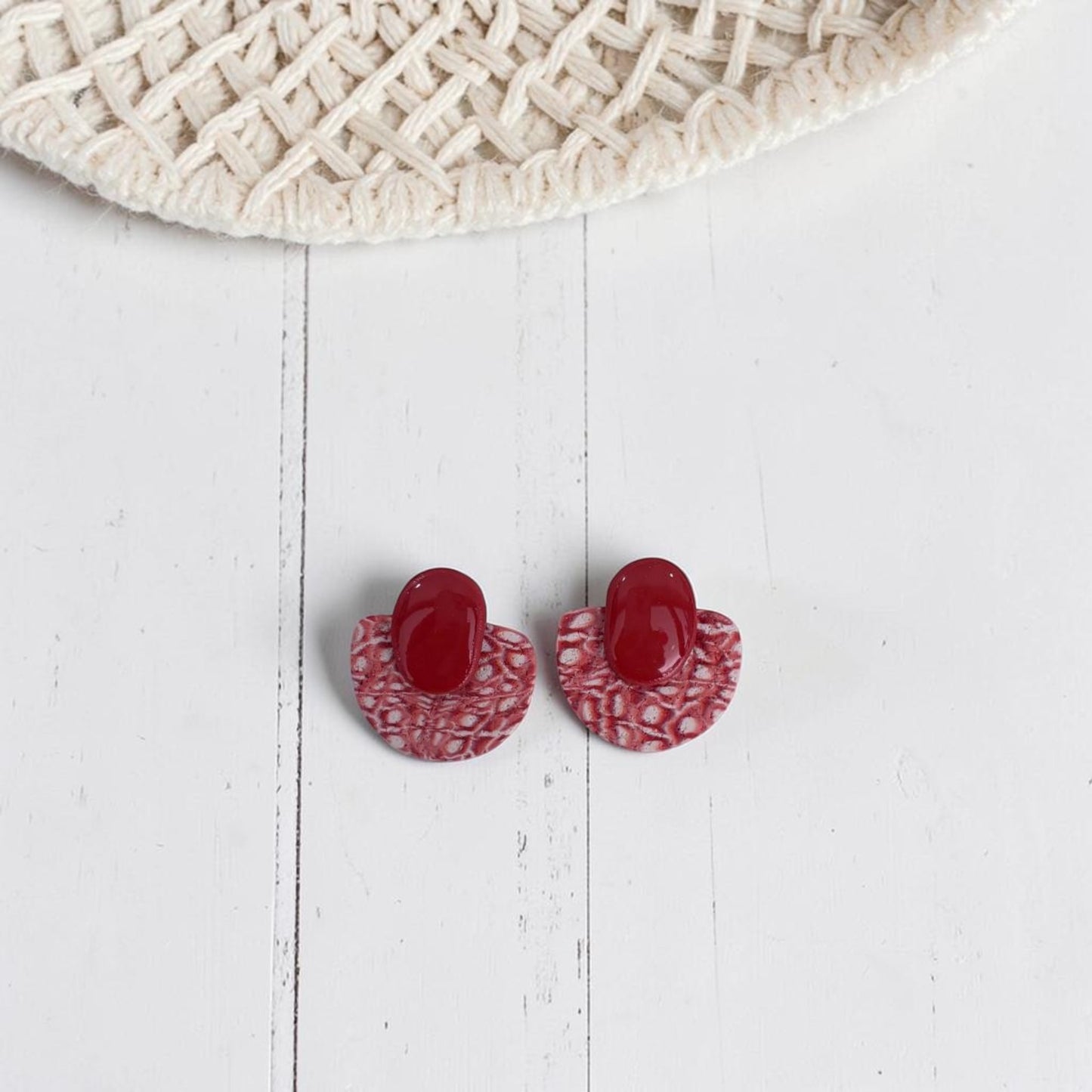 Pendientes Toffee color teja de arcilla polimérica con textura, vista del par completo sobre fondo de madera blanca con sombrero de paja