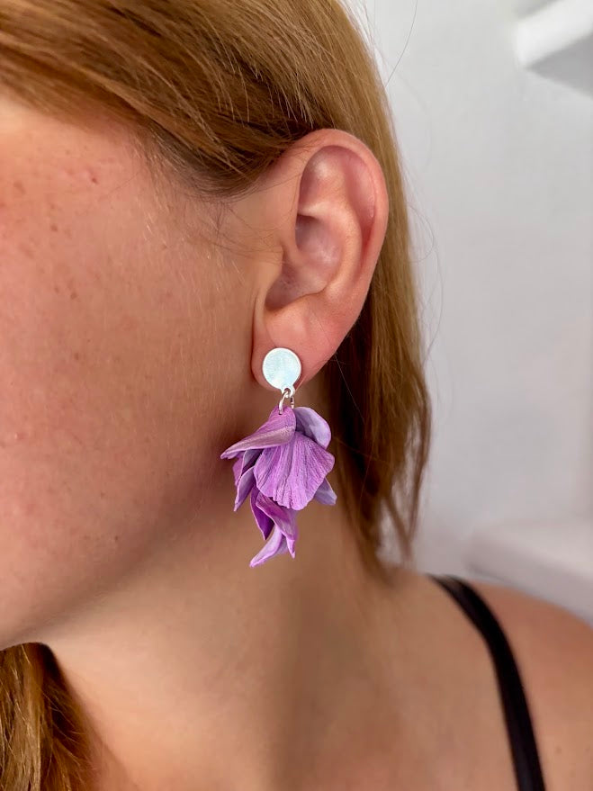 Primer plano de oreja con pendientes cascada de pétalos morados artesanales y enganche redondo  de plata en arcilla polimérica