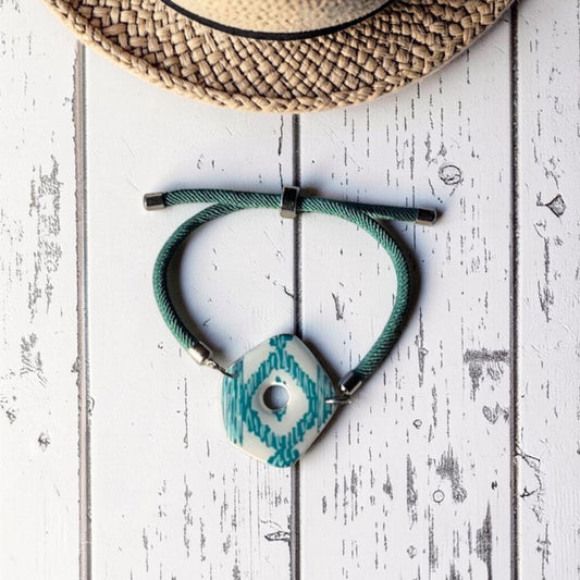 Pulsera verde de la colección Llengos Sol, con pieza central de arcilla polimérica pintada a mano con el dibujo típico de las telas de llengos mallorquinas y acabado en resina UV