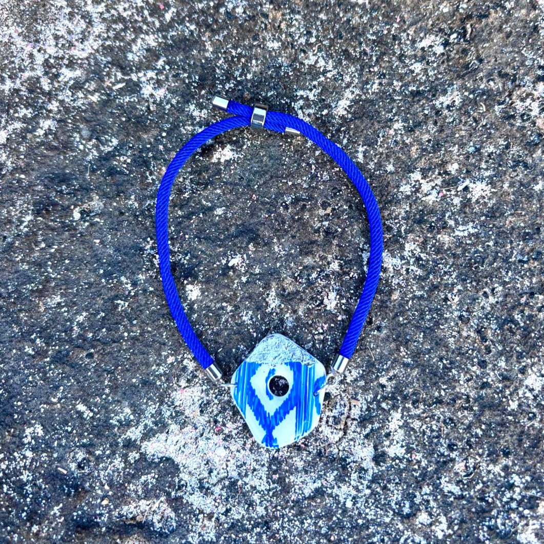 Pulsera mediterránea de diseño tradicional presentada sobre rocas naturales de la costa de Mallorca.