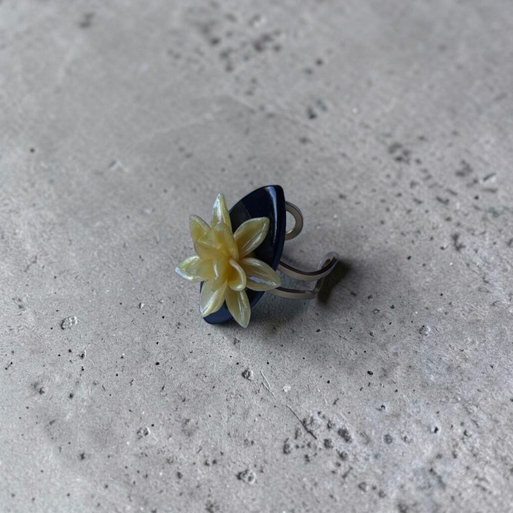 Anillo artesanal Modelo Galatzó con flor de dalia amarilla en arcilla polimérica sobre una base negra ovalada acabado en resina brillante y estructura ajustable