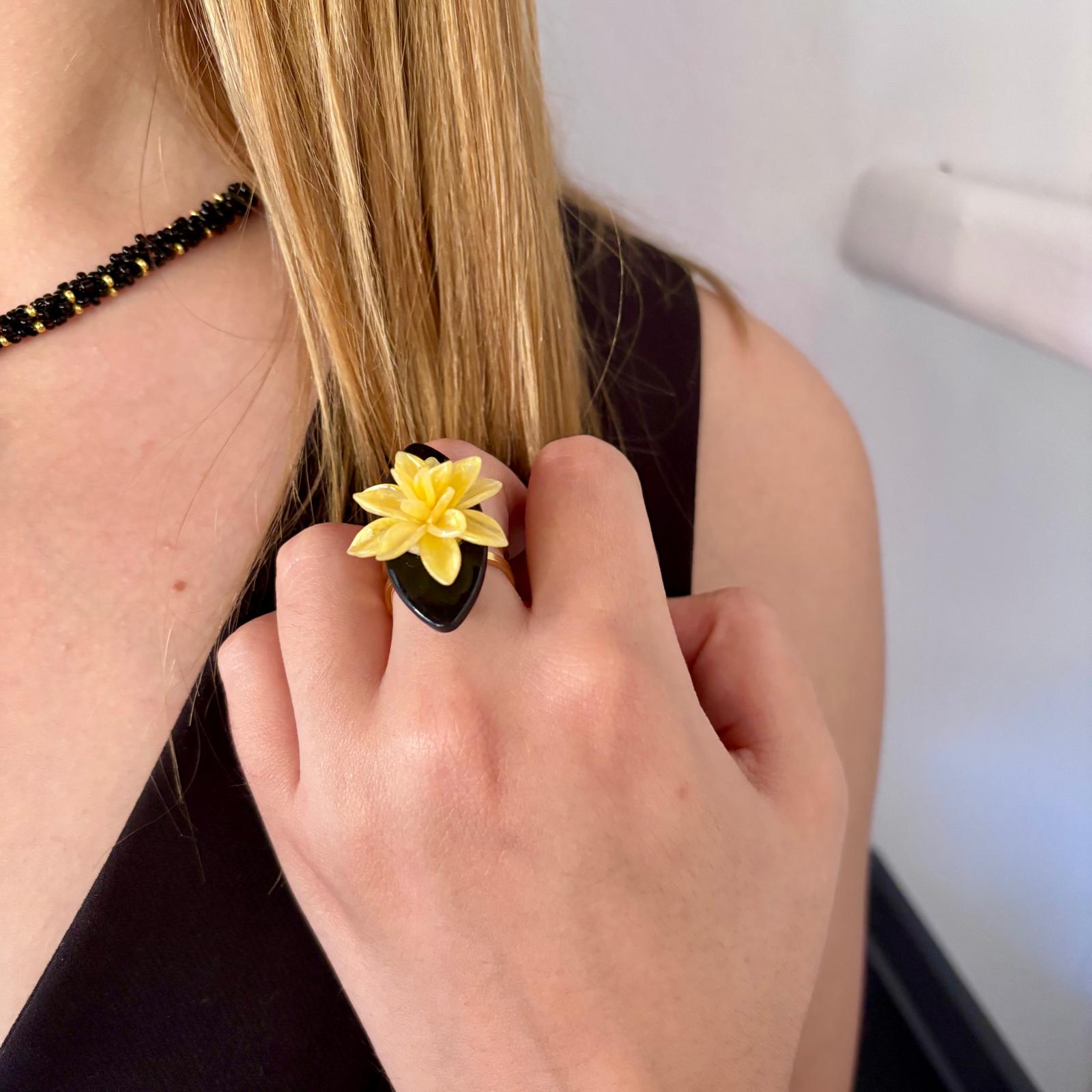 Detalle de la mano de una modelo con el anillo Galatzó ajustable, mostrando la flor amarilla modelada a mano sobre la base negra.