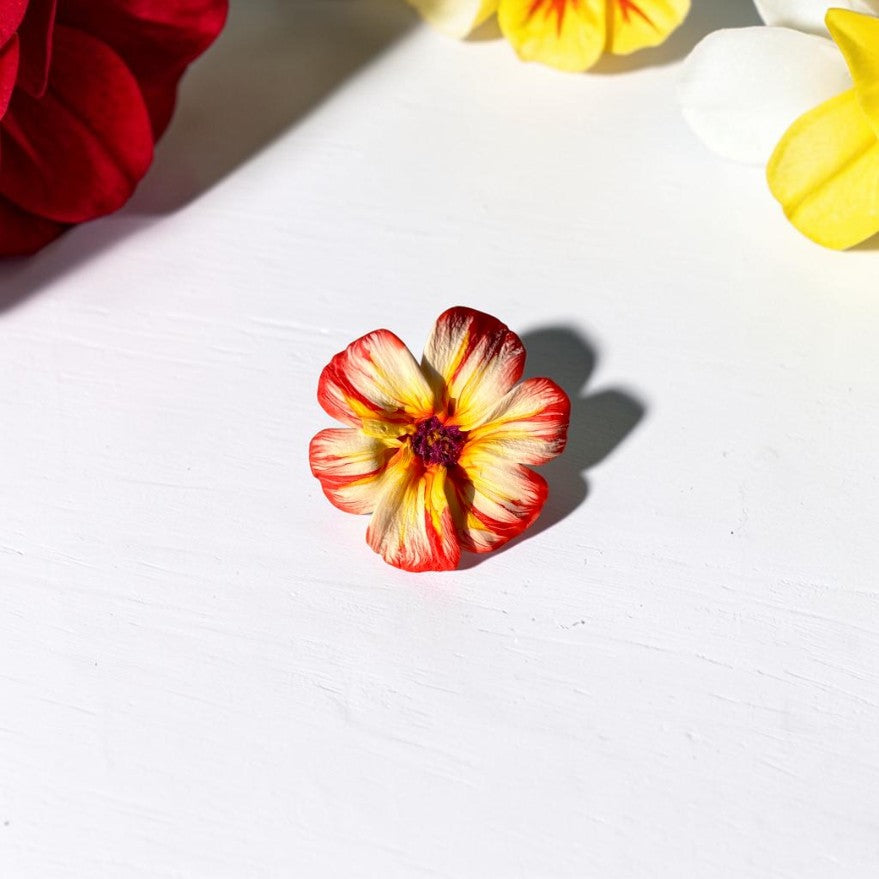 Vista frontal anillo flor de arcilla polimérica, artesanal, flor en tonos naranja,blanco y amarillo, centro en color morado