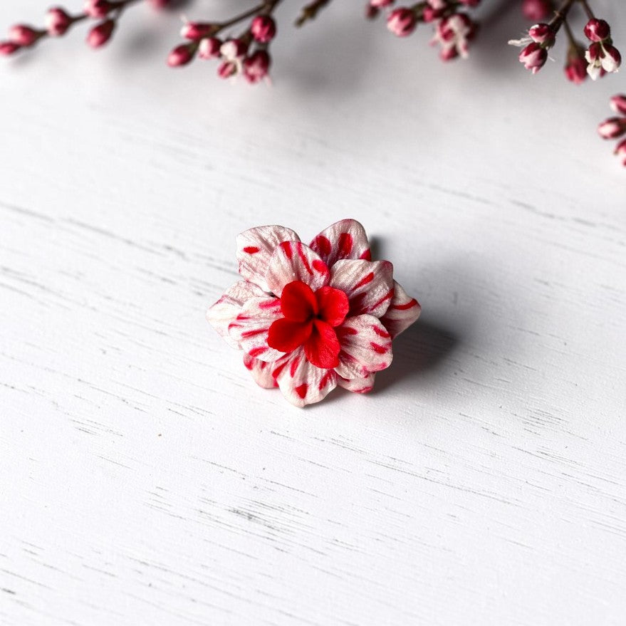 Vista frontal anillo flor de arcilla polimérica en tonos rosa y rojo con centro en color rojo