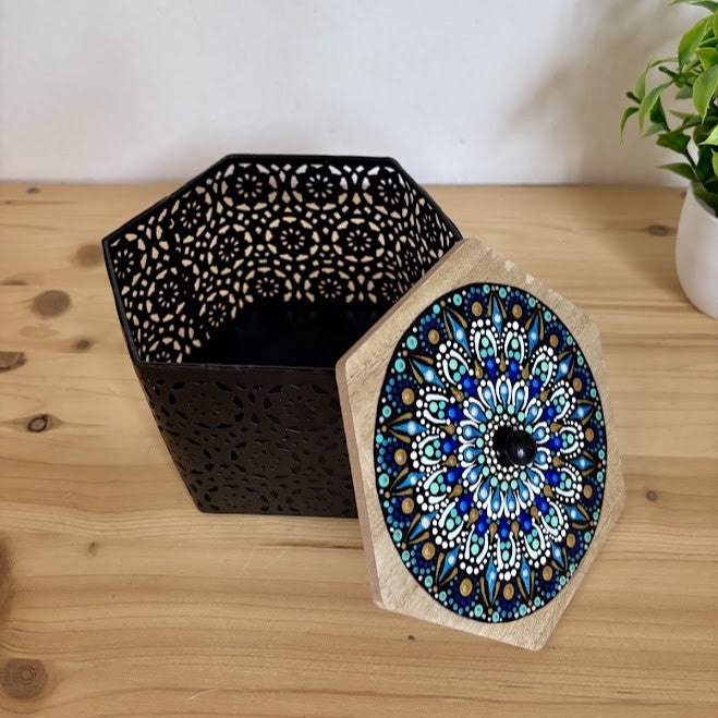 Caja metálica decorativa negra con diseño calado y tapa hexagonal de madera decorada con mandala artesanal en puntillismo azul y turquesa