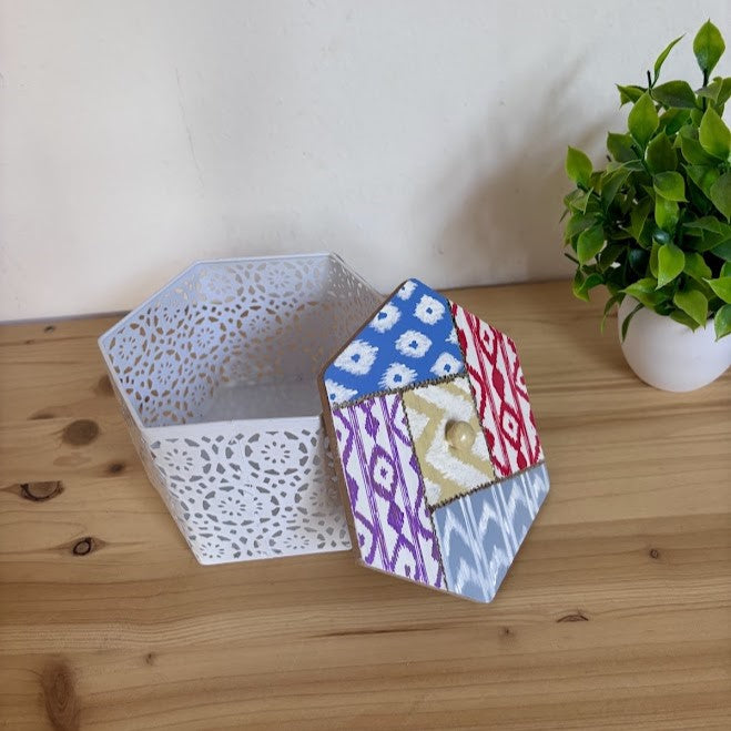 Cajita joyero hexagonal abierta mostrando la base de metal blanco y la tapa de madera artesanal con estampado tradicional de llengües de Mallorca.