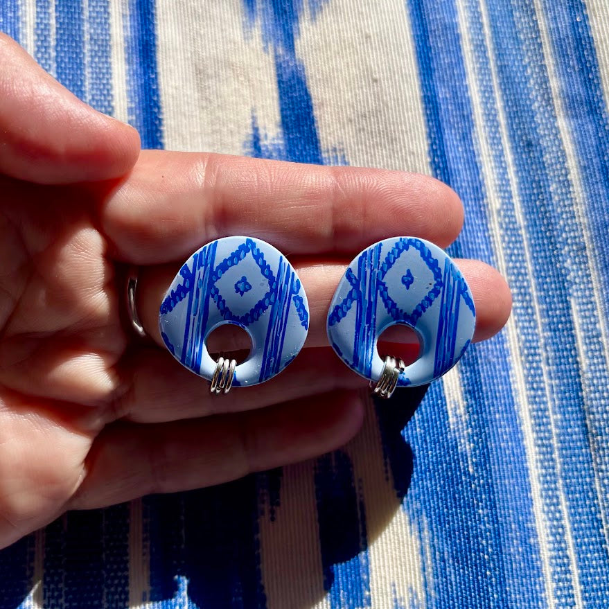 Pendientes llengos Cel de color azul sostenidos en mano apreciando su tamaño y detalle del pintado a mano