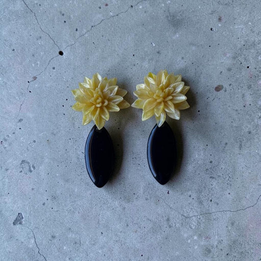 Pareja de pendientes Galatzó con diseño de flores amarillas artesanales y lágrima de color negra acabada en resina de alto brillo, estilo elegante para eventos.
